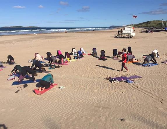 Group of ladies doing yoga on the beach