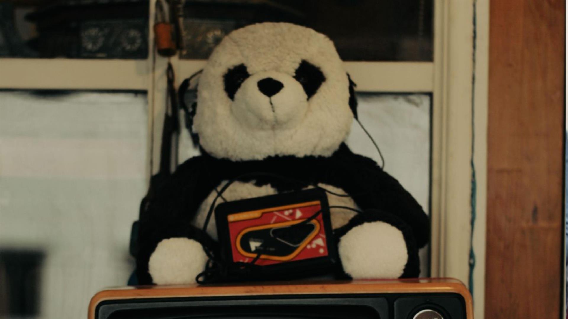a stuffed panda toy is listening to a toy tape player with headphones a stuffed panda toy is listening to a toy tape player with headphones