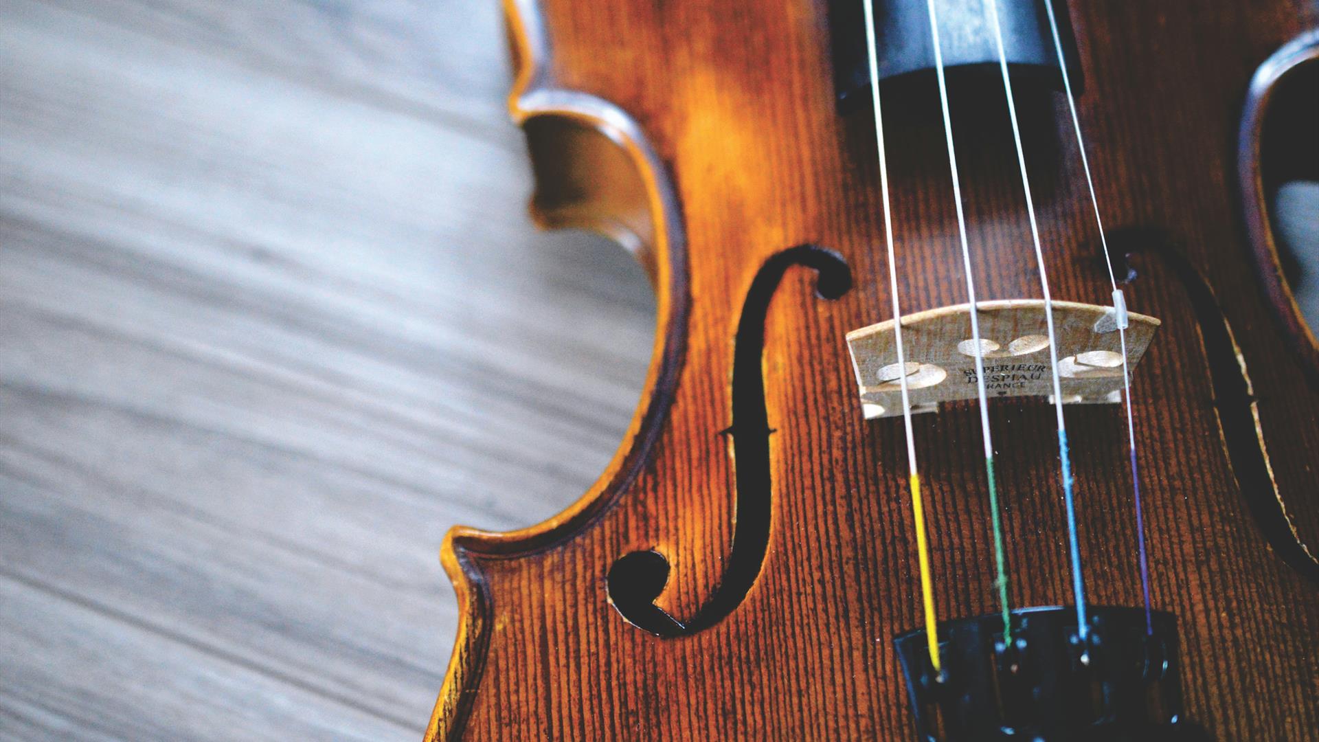 close up of violin sitting on a wooden surface close up of violin sitting on a wooden surface