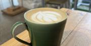 a cup of coffee with latte art in a green ceramic mug