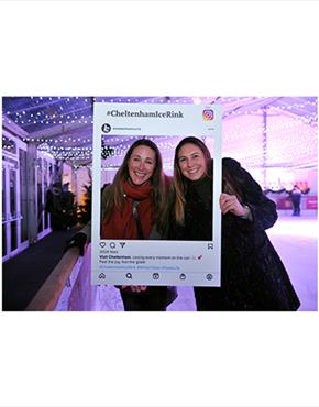 Friends posing with an Instagram selfie sign at the Cheltenham Ice Rink