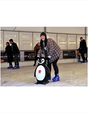 A woman with a penguin skate aid at Cheltenham Ice Rink