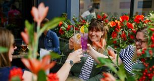 A group of women raising a toast with colourful cocktails in Flight Club's flowery summer terrace