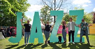 People stood next to big JAZZ sign.