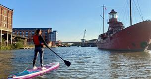Paddle boarding on Gloucester docks in front on Sula Lightship