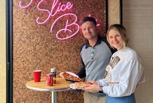 A couple eating pizza at Slice Bros