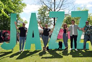 People stood next to big JAZZ sign.