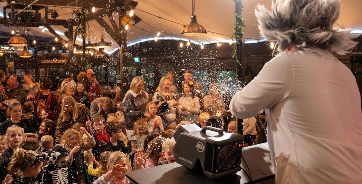 A man dressed as a crazed scientist entertaining a crowd of children with balloons at Dunkertons Cheltenham