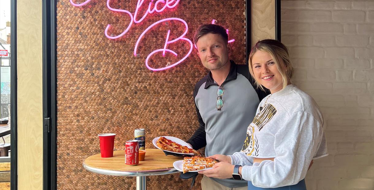 A couple eating pizza at Slice Bros