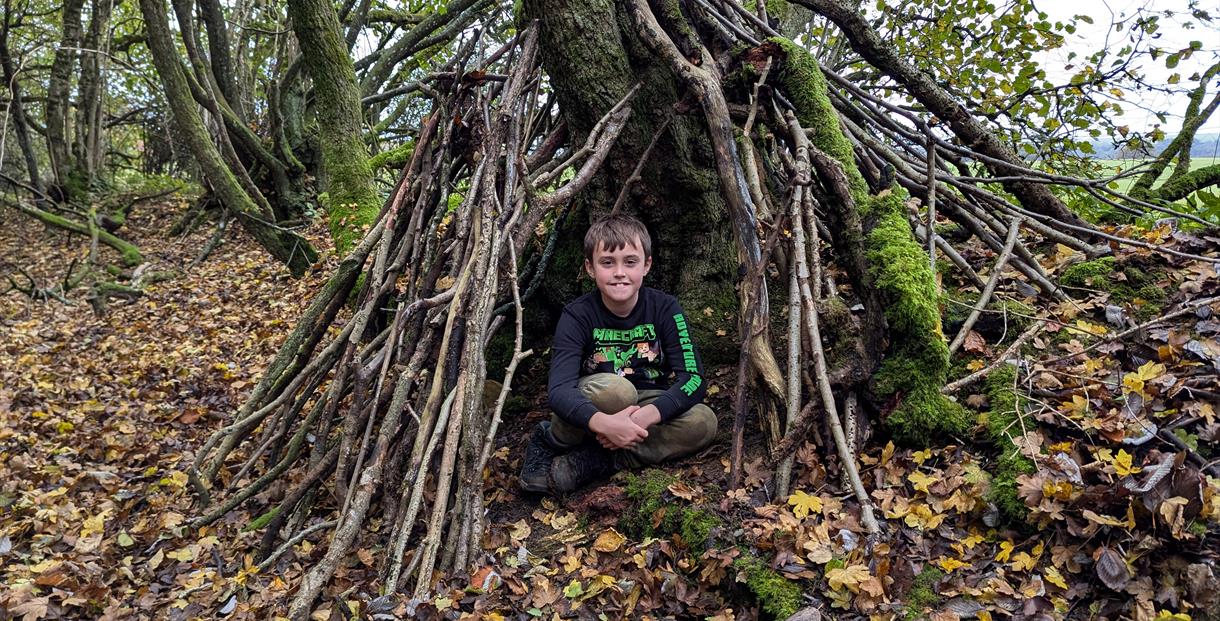 Boy in a den made from sticks