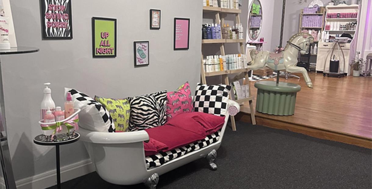 Inside the salon, a comfy sofa made from an old roll-top bath, colourful pictures in frames on the wall and a fairground carousel horse.