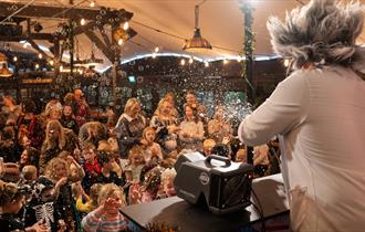 A man dressed as a crazed scientist entertaining a crowd of children with balloons at Dunkertons Cheltenham
