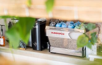 A coffee machine framed by green leaves