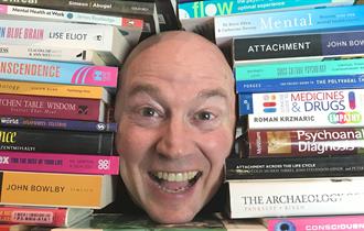 Dr Sice's smiling face amid piles of self help books
