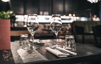 A set dining table at Brasserie Blanc Cheltenham, with two wine glasses and a menu