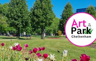 A photo of the imperial gardens park where art in the park will take place showing white and pink tulips in the foreground, tall green trees against a