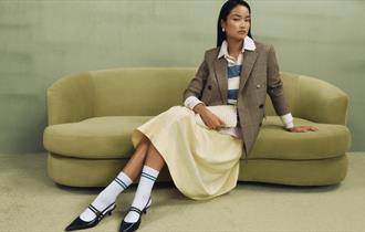 Model sitting on a pistachio coloured sofa