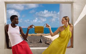 Two models holding a handbag