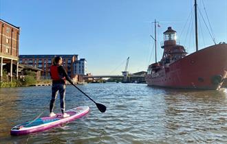 Paddle boarding on Gloucester docks in front on Sula Lightship