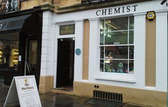 Spa Pharmacy's traditional stone shop front with blue plaque