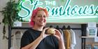 A Steamhouse employee holding a bagel
