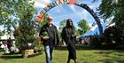A couple walking in front of the Cheltenham Jazz Festival sign arch.