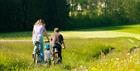 A family cycling through a field