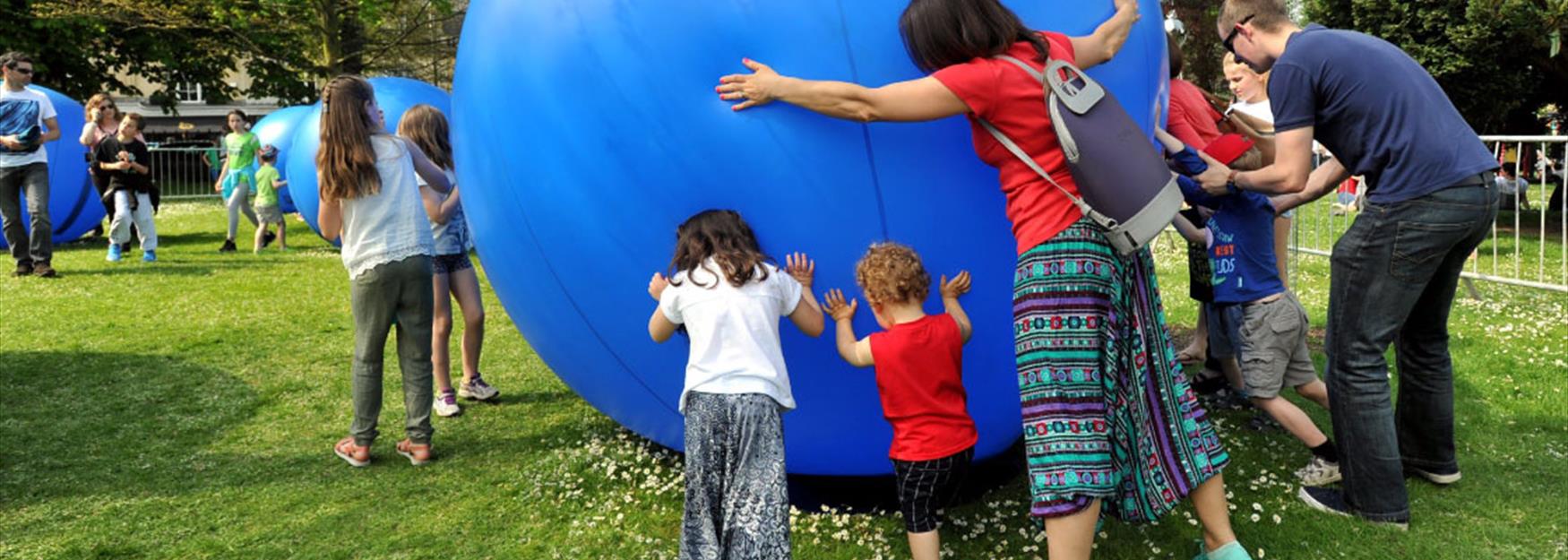 Family rolling a huge inflatable ball at one of Cheltenham's festivals