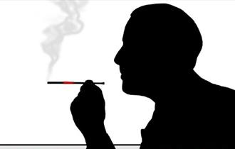 A sillhouette of a man smoking a cigarette