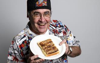 Danny baker holding a plate of sausages