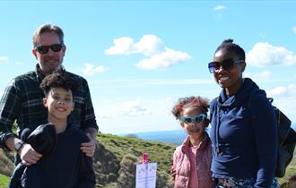 Family stood on Cleeve Common with an Easter trail sign