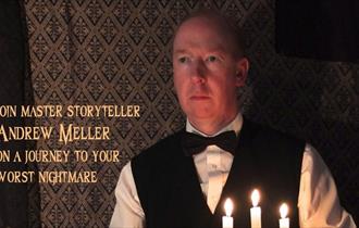 Andy Meller dressed as a butler holding a candle