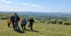 a family walking on Cleeve Common with sweep nets and a far reaching view behind them