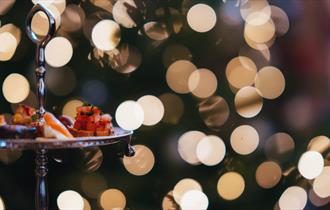 An afternoon tea tray against a backdrop of fairy lights