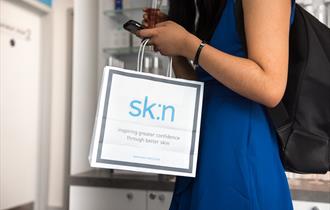 Lady carrying a sk:n branded bag