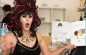 A drag queen reading a story book
