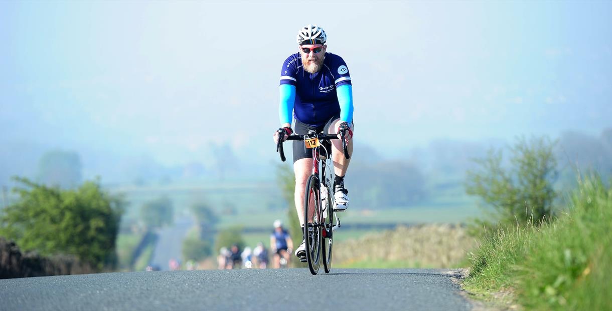 A cyclist crests a hill in the English countryside
