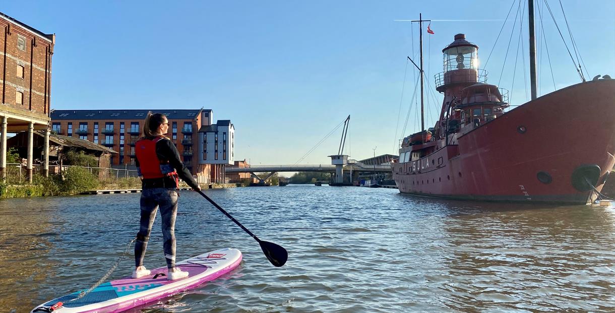 Paddle boarding on Gloucester docks in front on Sula Lightship