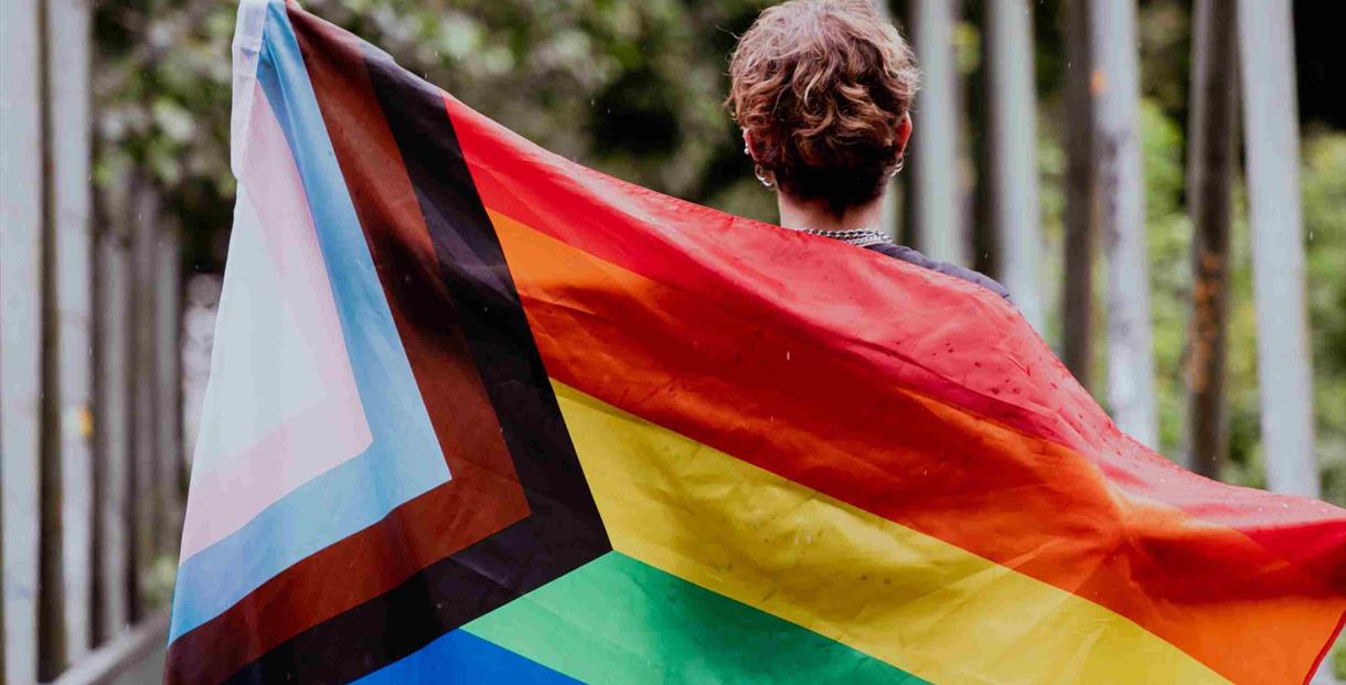A woman holding a LGBTQ+ flag
