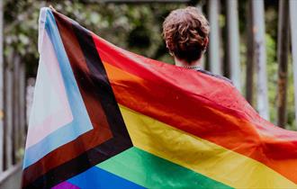 A woman holding a LGBTQ+ flag