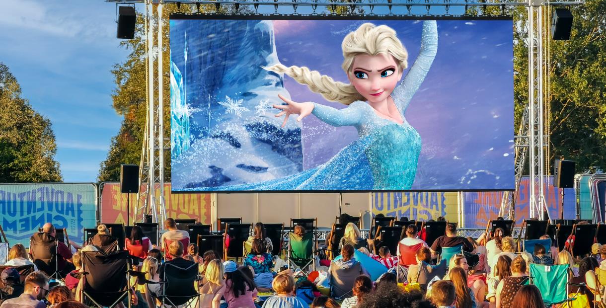 Frozen film playing on outdoor cinema screen with crowds watching