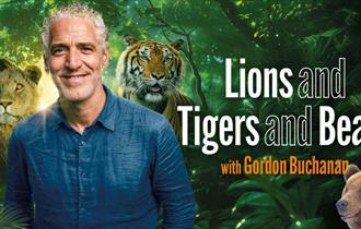 Gordon Buchanan standing in front of trees and a lion, tiger and bear