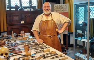 Tudor Surgeon with a table of surgical instruments