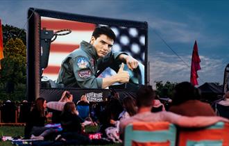 Top Gun film playing on outdoor cinema screen with crowds watching
