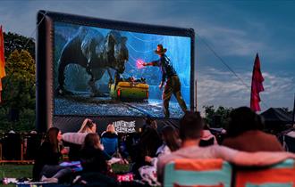 Jurassic Park film playing on outdoor cinema screen with crowds watching