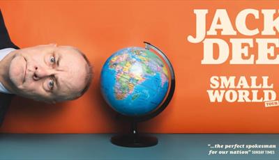 Jack Dee sideways next to a globe