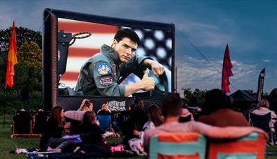 Top Gun film playing on outdoor cinema screen with crowds watching