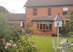 Well maintained back garden with patio furniture and rose bushes