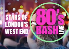 a blurred image of the back of peoples heads stood at a concert. A lady is holding her fist up in the air. The title of the show, 80's Bash is in pink