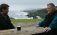 Colin Firth and Brendan Gleeson sat drinking stout with the Irish coastline in the background